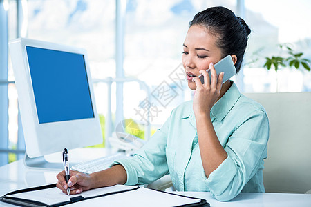 微笑的女商务人士打电话问话办公室快乐老鼠触摸屏手机床单旋转键盘商务笔记本图片