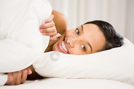 在床上微笑的黑发女人图片