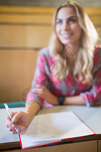 课堂上微笑的女学生学生教科书笔记学校演讲考试知识修订团队桌子图片