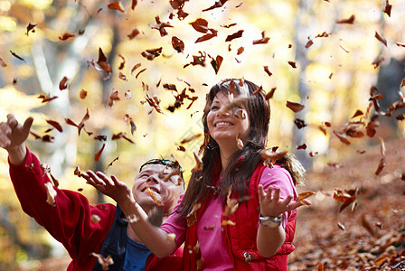 年轻夫妇享受落叶的假期孩子男人幸福女性树叶快乐森林女士阳光微笑图片