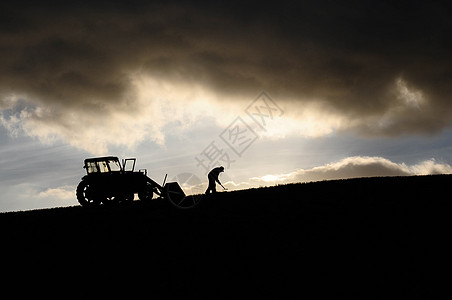 农民在云中高空的拖拉机旁边工作的轮椅图片