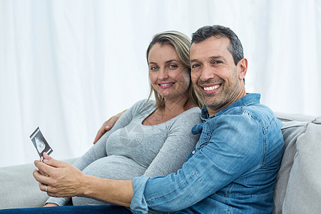 一对夫妇在看超声波扫描客厅沙发微笑男人快乐分娩住所生育力感情孕产图片
