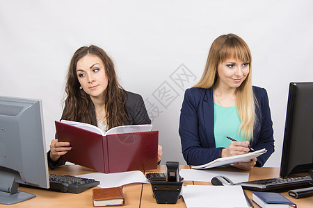 两名商业妇女在一个对立桌面上工作图片