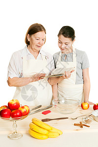 外祖母和孙女读食谱的秘方书厨房女性专家衣服烘烤女孩食物红色阅读糕点图片