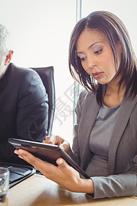 使用数字平板的有吸引力的商业妇女技术套装办公室专注工人会议桌触摸屏职业互联网会议室图片