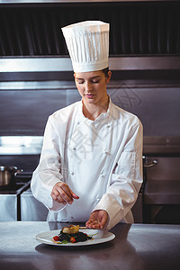 主厨在菜盘上喷洒香料厨师食物美食厨师长大楼女性酒店准备工作白人图片