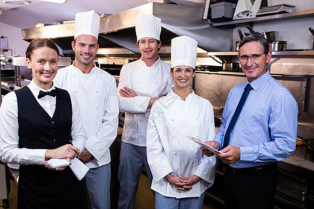 欢乐餐饮团队在商业厨房里站在一起滚刀记事本服务器合作同事餐厅煤气灶马甲职业职员图片