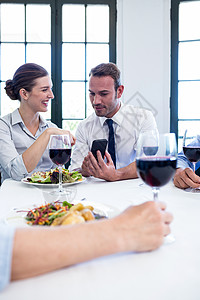 商界同事在商业午餐会议期间看移动电话问题 b 企业午餐会酒杯生意人商务人士酒精伙伴合伙阅读沟通滚动图片