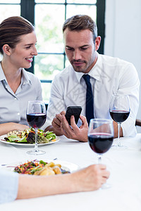 商界同事在商业午餐会议期间看移动电话问题 b 企业午餐会阅读酒精手机女士沟通桌子女性酒店管理人员生意人图片