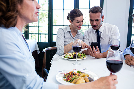 商界同事在商业午餐会议期间看移动电话问题 b 企业午餐会互动合伙快乐男性沟通女性伙伴桌子酒精阅读图片