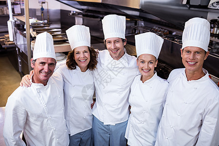 欢乐厨师团队在商业厨房里站在一起快乐工作同事微笑白人制服男性双臂女士伙伴图片