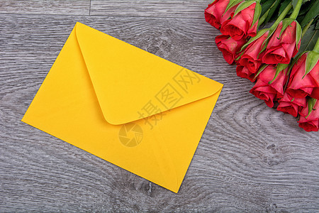 黄色信封和木制背景的玫瑰花朵绿色装饰桌子卡片红色风格木板木头假期图片