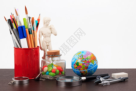 带有创意配饰的艺术品工作场所 白色背景上的创意艺术作品教育杯子学生雕塑笔记本画笔刷子艺术家桌子铅笔图片