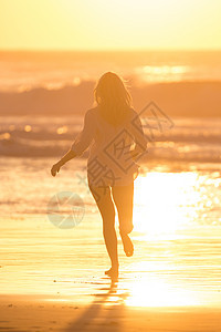 女人在日落的海滩上奔跑女士闲暇海岸假期背光太阳成人海洋生活晴天图片