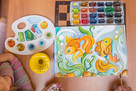 鱼皮画在纸金鱼上画水彩的桌子上的顶端视图背景