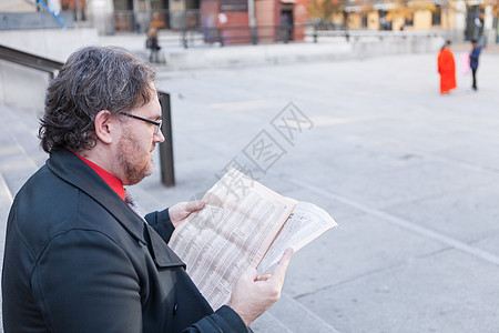 年青商务人士与一家报纸商务手机人士药片管理人员男性出版物男人城市经济图片