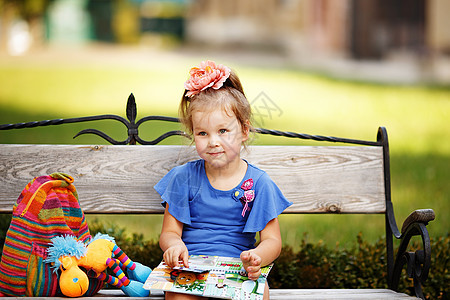 一个小女孩的肖像 读儿童书 在公园上是女性乐趣童话故事学习教育微笑情感玩具童年快乐图片