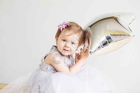 一个穿着优雅灰色礼服的可爱小女孩的肖像喜悦气球玩具娘娘快乐冒充孩子金发女郎乐趣婴儿图片