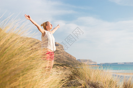 自由快乐的女子在节日中享受阳光天空冥想喜悦生活女孩女性幸福海滩头发旅行图片