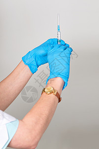 双手将注射器放在橡胶医疗手套中图片