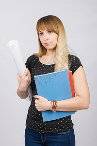 年轻女孩拿着文件夹和一卷纸 在悲伤的向前看的手手里图片