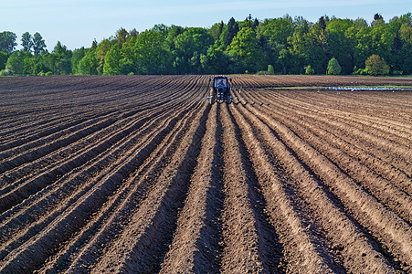 拖拉机在犁田上进行种子钻探天气蓝色森林技术地平线地球土地衬套农业车辆图片