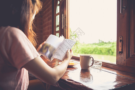 妇女阅读书籍和享受新鲜咖啡或茶叶的生活方式图片