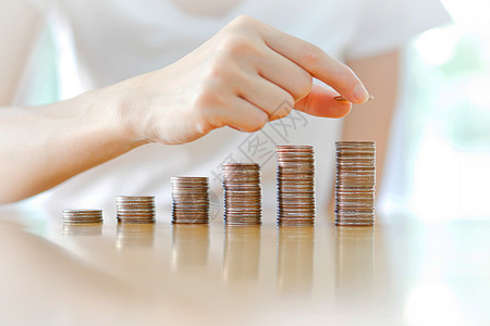 储蓄 商业妇女把硬币堆叠成越来越多的柱子图片