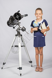 女学生天文学家是一个望远镜 手握着一个地球和书籍图片