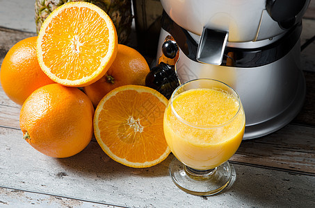 木制桌上玻璃杯中的果汁和橙汁菠萝用具制作者提取器食物橙子房子机器搅拌机水果图片