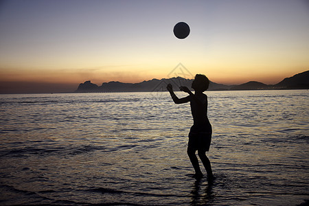 海滩日落时踢足球太阳男生天空孩子热带阳光海洋运动晴天旅游图片
