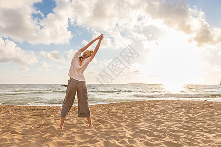 日落时在海边做瑜伽的女人海滩活力平衡运动女士女孩阳光海洋身体训练图片