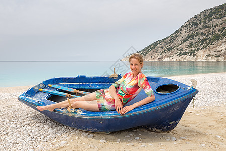 女人躺在希腊海滩的划船船上图片