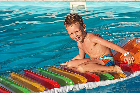 快乐的孩子在蓝水游泳池玩蓝色充气运动床垫闲暇情绪假期水池乐趣微笑图片