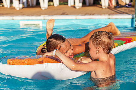 孩子们在游乐场孩子们在游泳池的蓝水里玩得开心游泳者乐趣幸福充气酒店水池床垫游泳气垫女孩背景
