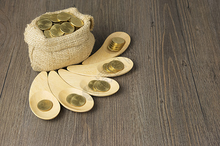 木勺中的金币和棕色硬币袋用具硬币勺子金子解雇木头商业图片