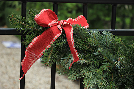 圣诞园地在围栏上房子庆典红色金子栅栏假期松树绿色背景图片