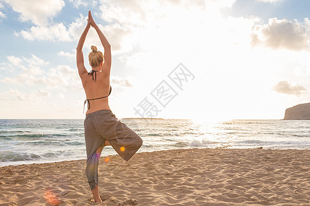 日落时在海边做瑜伽的女人阴影女士海洋阳光身体女性运动装平衡支撑天空图片