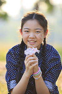 12岁的泰国女孩坐在花园田地上 花朵粉红图片