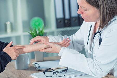女性病人在整形外科医生对手腕伤害进行医学检查时保健从业者疼痛职业考试卫生医师骨科药品诊断图片