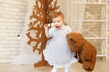 内地有柔软棕褐色泰迪熊的漂亮女婴婴儿庆典喜悦乐趣裙子童年新年玩具公主快乐图片