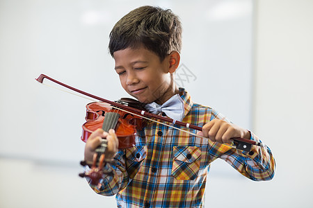 在课堂上玩小提琴的男生服装教育学生眼睛专注学校乐器童年休闲混血图片