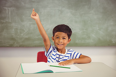 男孩在课堂上举手的肖像微笑笔记本混血教育知识警报休闲小学生桌子学校图片