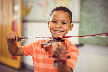 在课堂上玩小提琴的微笑男孩的肖像爱好学习音乐黑色休闲小学生乐器童年学生快乐图片