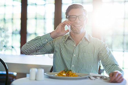 享受男人在午餐时用手机聊天的快乐电子椅子男性桌子互动微笑盘子技术午餐电脑图片