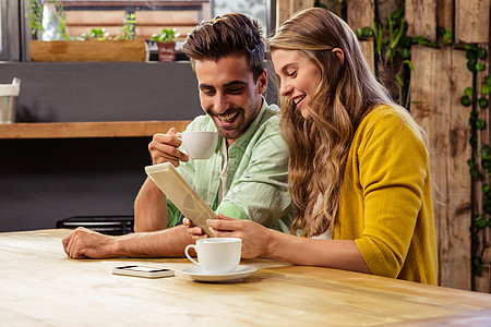 使用平板电脑的可爱夫妇讨论互动微笑触摸屏饮料咖啡餐厅快乐女性男性图片