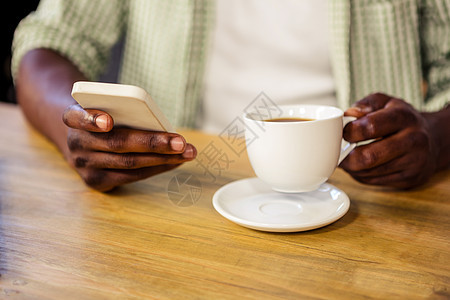 使用智能手机时手握咖啡杯的手图片