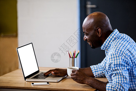 持有咖啡和在笔记本电脑打字的商务人士概况图片