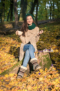 女孩坐在树桩上公园幸福情感晴天糖果咖啡森林太阳牛仔裤乐趣图片