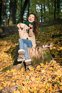 女孩坐在树桩上橙子黑发太阳树叶女儿森林乐趣微笑幸福花园图片